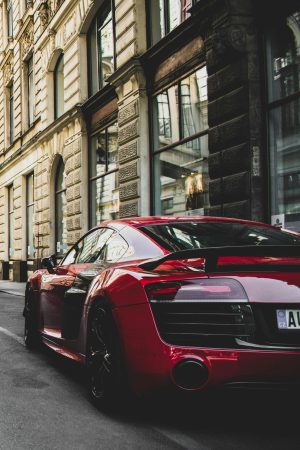 Sleek red sports car parked on a charming historic street in Prague, highlighting urban elegance and powerful design.